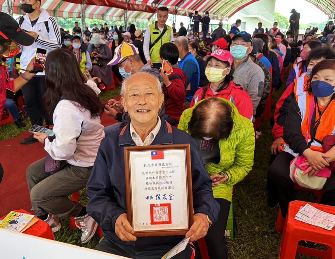恭喜本區偵水志工隊榮獲市府表揚，由 東山里 高健市里長 代表上台受獎